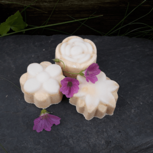 3 savons en forme de fleurs posés sur une ardoise