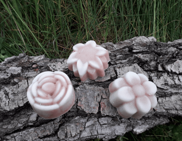 3 savons en forme de fleur posés sur une écorce